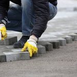 Paving stone worker is putting down pavers during a construction of a city street.